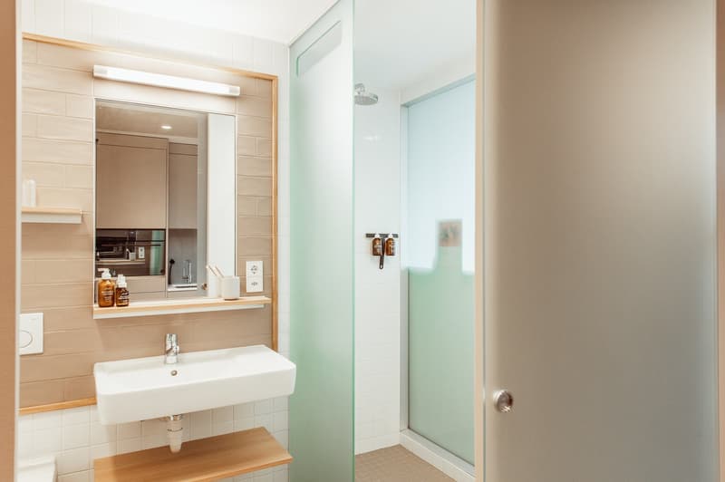 Bathroom with white sink, mirror, shower, and tiled walls.