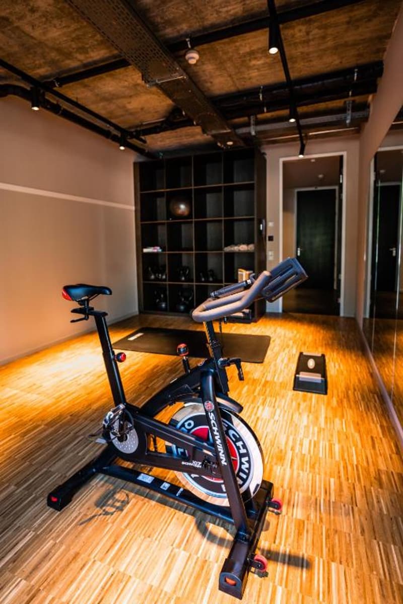Spin bike, wooden floor, exposed ceiling beams, shelving unit
