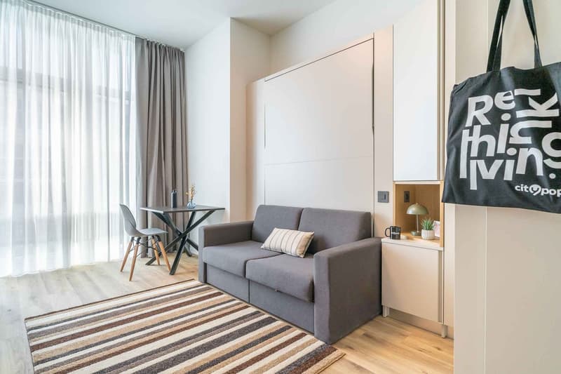 small living room with sofa, table, chair, rug, and white walls