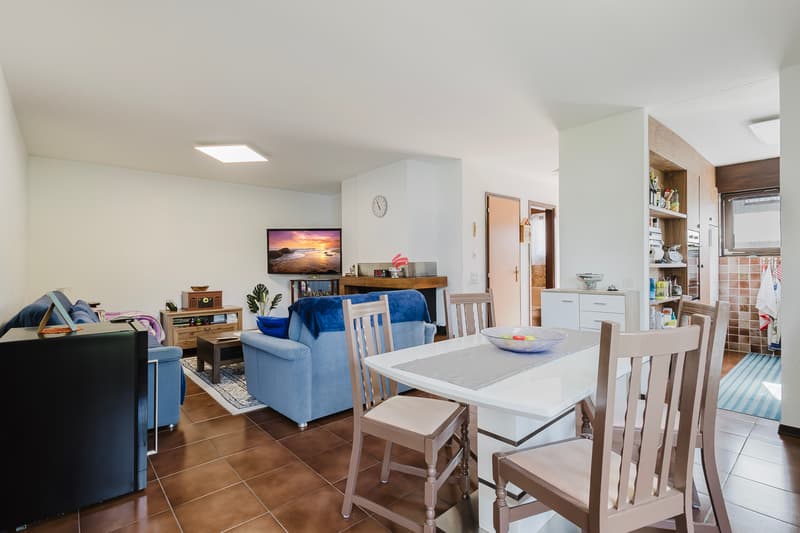 Das Wohnzimmer befindet sich in der Mitte der Wohnung und verbindet somit alle Bereiche. Im Eingangsbereich steht zudem ein praktischer kleiner Abstellraum zur Verfügung. / Il soggiorno al centro del
