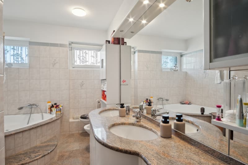 Grosszügiges Bad mit Doppelwaschbecken und Eckbadewanne.