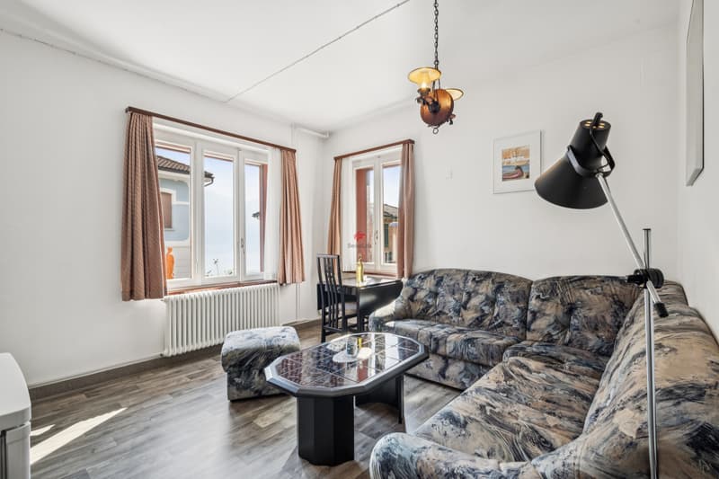 Auch das Wohnzimmer im Erdgeschoss wird dank zweier Fenster mit reichlich Sonnenlicht und Aussicht auf den See verwöhnt. / Anche nel soggiorno al pianterreno si ha il privilegio di ricevere molta luc