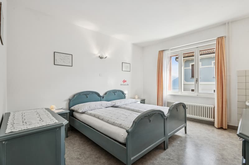 Das grosszügige Schlafzimmer der Einliegerwohnung verfügt über ein Lavabo im Raum und liegt direkt gegenüber der Nasszelle. / L'ampia camera da letto dell'appartamentino al pianterreno dispone di