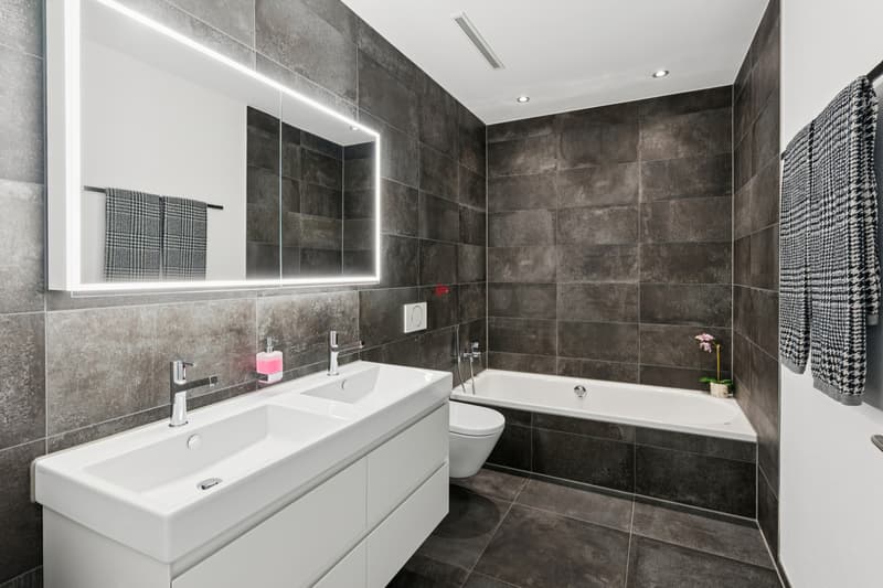 Das stilvolle Hauptbad mit Doppellavabo und komfortabler Badewanne lädt zum Entspannen ein.