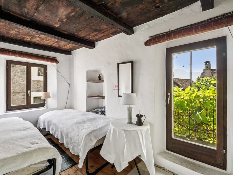 Vom Schlafzimmer mit Holzschrank im mittleren Geschoss gelangt man auf den Balkon. / Dalla camera al piano intermedio, dotata di armadio, si accede al balcone.