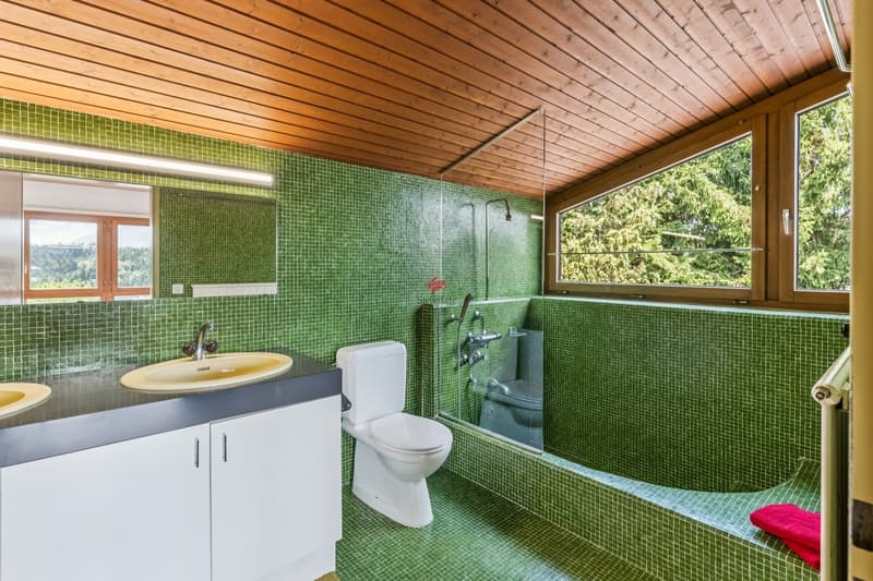 Auch das Badezimmer en Suite besticht durch seinen aussergewöhnlichen Ausbau und den entspannenden Blick ins Grüne.
