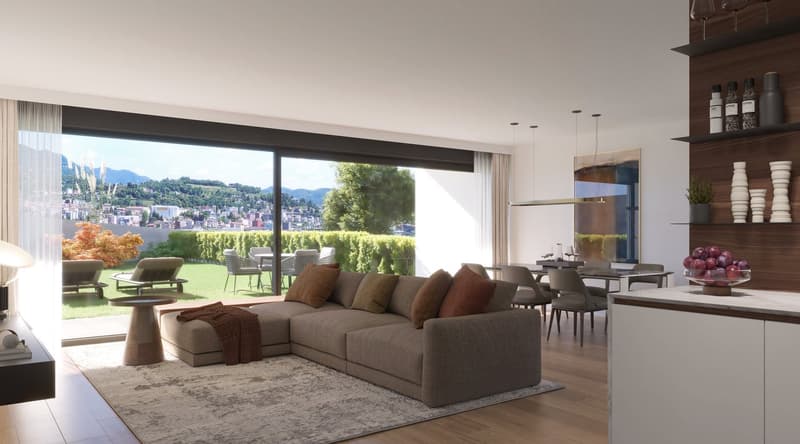 Spacious open-plan living room with large windows offering a scenic view of the surrounding mountains and cityscape. The room features a comfortable L-shaped sofa, a dining table with chairs, and a modern kitchen area with shelving and appliances. The dec