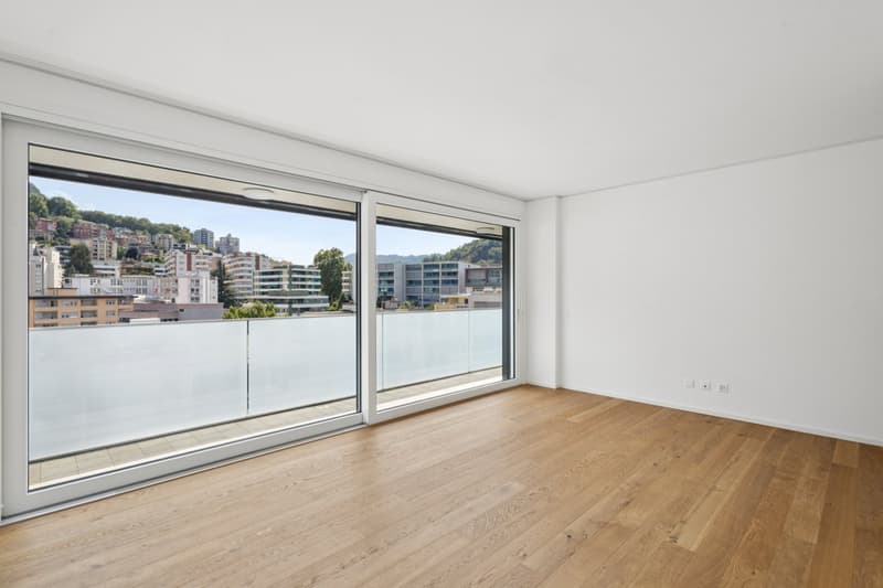 Empty room, wooden floor, white walls, large glass sliding doors, balcony with view, power outlets
