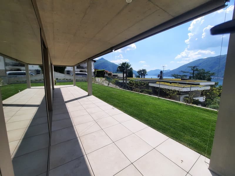 terraced area with tiled flooring and large windows overlooking a manicured lawn and scenic view
