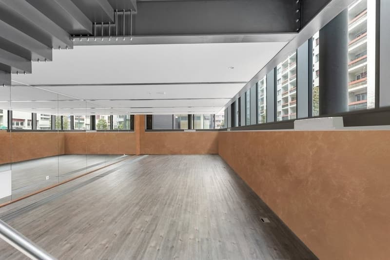 Open corridor, with large windows, glass walls, hardwood floors, exposed ceiling with metal beams