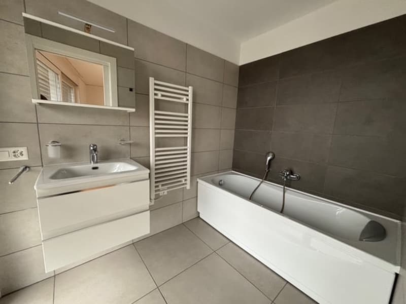 a bathroom with bathtub, sink, mirror, toilet paper holder, and towel rack