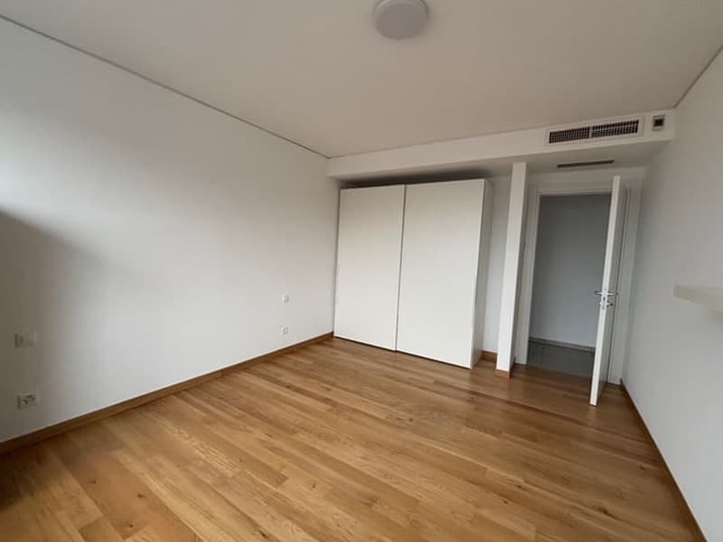 Large room with hardwood floors, white walls, two large white closets, white door