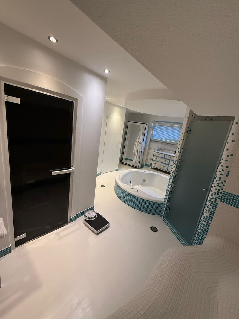 Spacious bathroom with large bathtub, walk-in shower, towel racks, small desk, scale, modern lighting