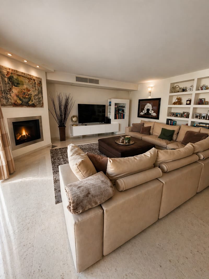 large L-shaped sofa, fireplace, flat screen TV, coffee table, rug, bookshelves, decorative items