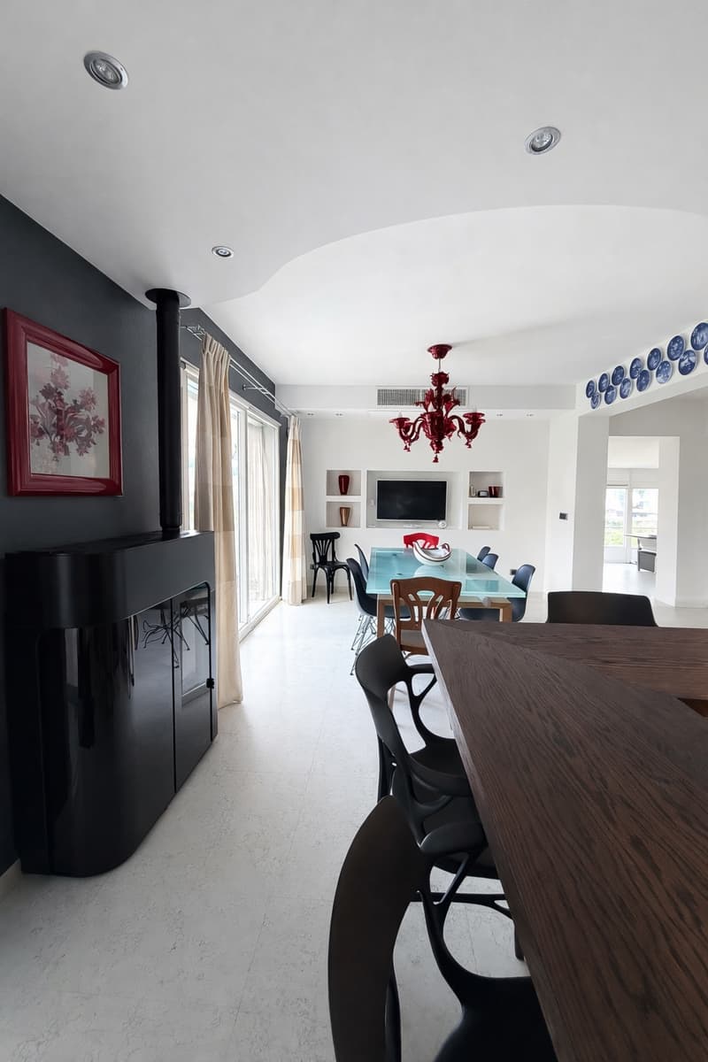 modern dining room with a fireplace, chandelier, glass table, chairs, and a television