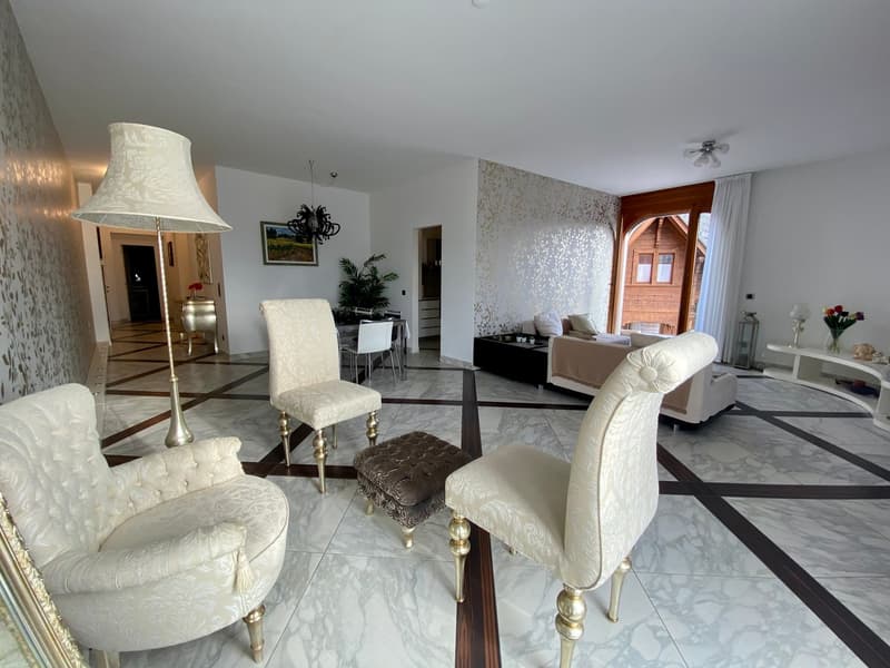 Modern interior with white upholstery furniture, white walls, patterned tiled flooring, a tall standing lamp, and a chandelier