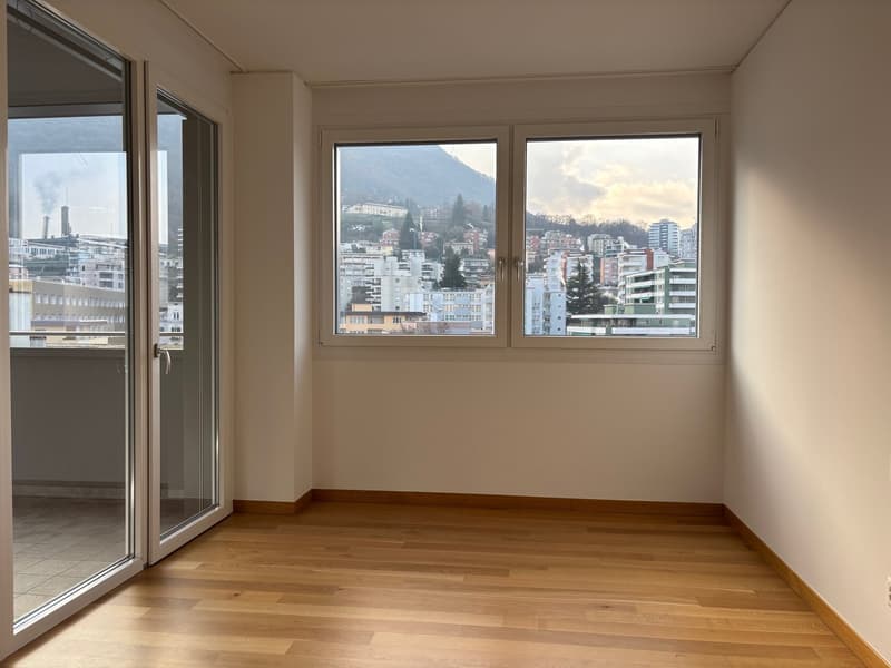 empty room with wooden floor, white walls, large windows with balcony access, mountain view