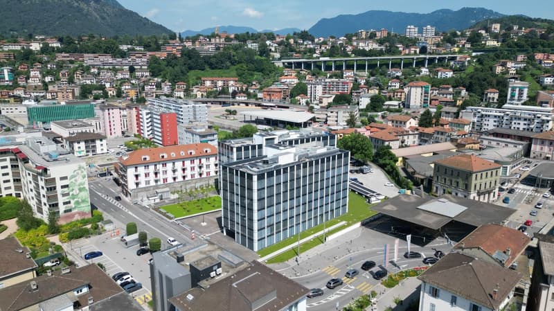 Aerial view of city with a glass building and mountain range in the background