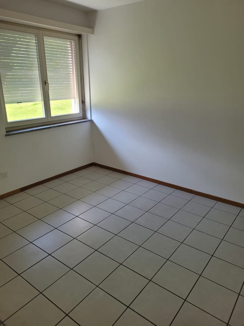 Empty room with white walls, tile flooring, and a window with blinds.