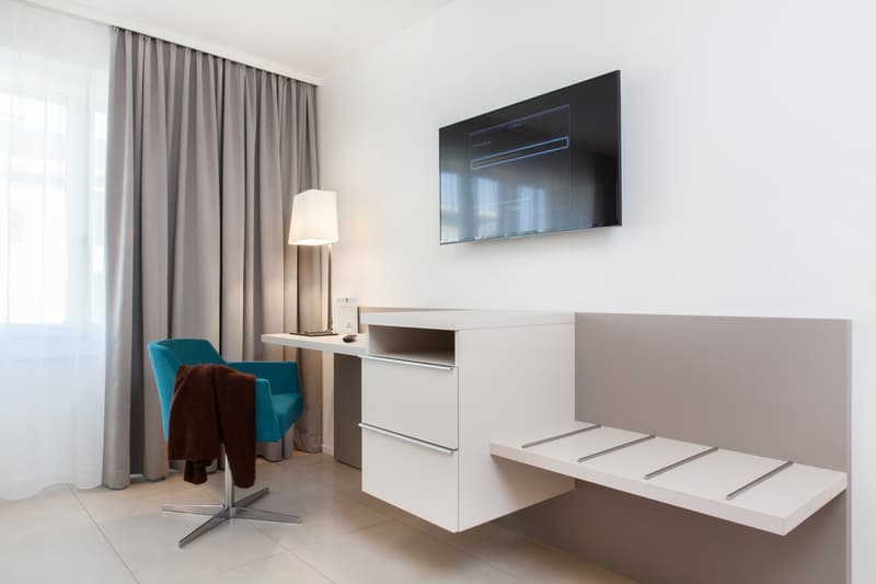 modern room with a desk, flat screen TV, blue chair, lamp, and a folded brown towel