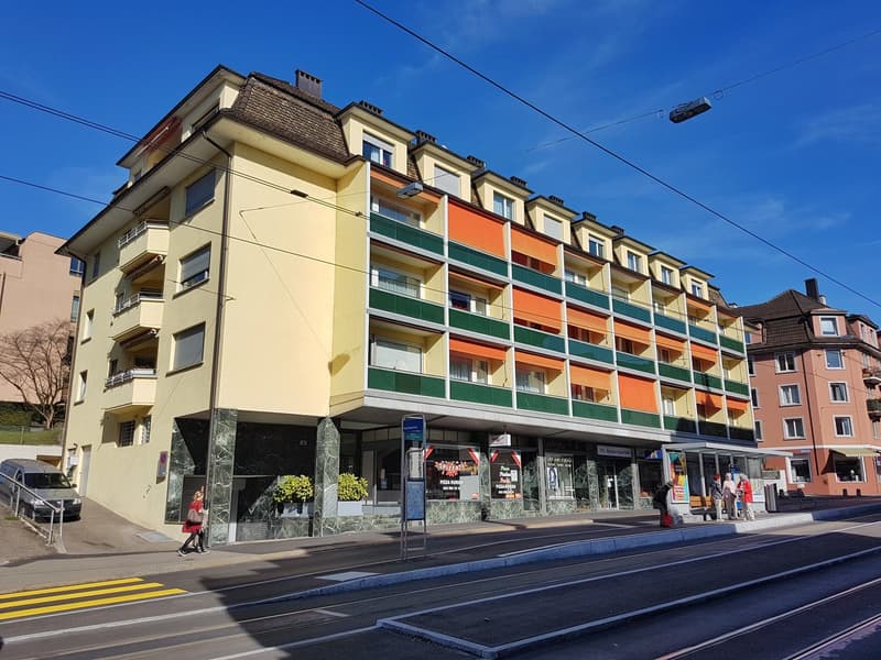 Multiple floors, yellow and orange color scheme, multiple balconies, large windows, trees and street lights nearby
