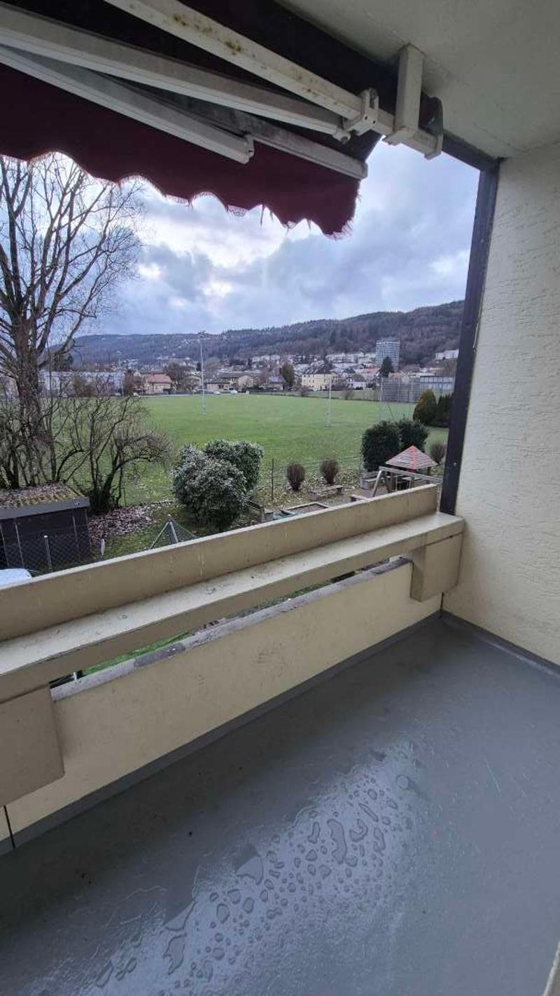 Terrace with concrete floor, overlooking a green field and town