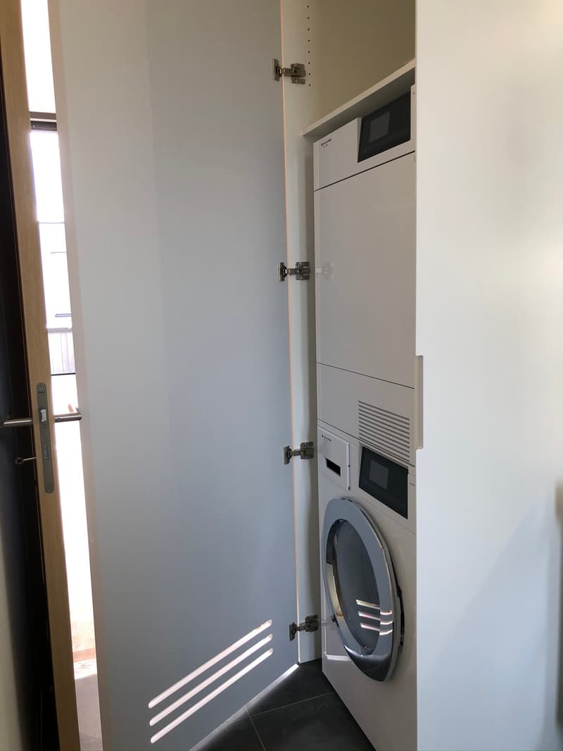 A small room with a white door, a washing machine, and a dryer.