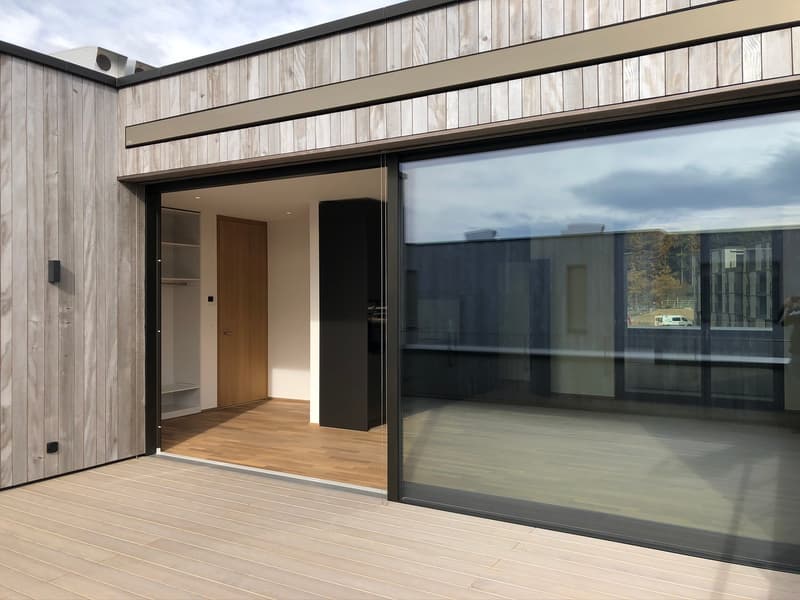 wooden exterior wall, sliding glass door, wooden deck, large glass window