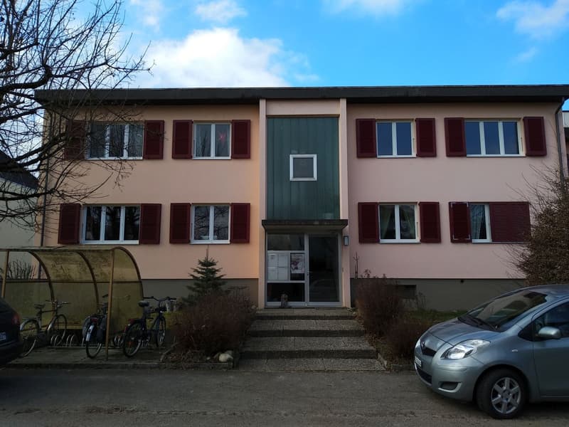 Multi-unit residential building with 4 floors, red shutters, entrance with a small staircase, bicycles parked in front