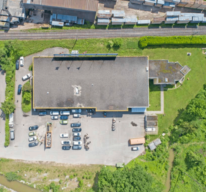 Large building with an attached parking lot and vehicles parked in it.