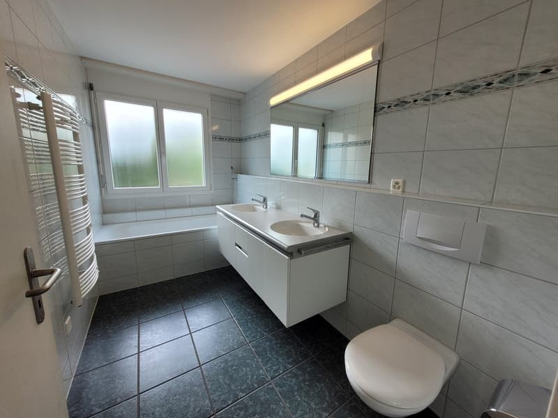 Bathroom with bathtub, double sink, toilet, mirror and wall heater