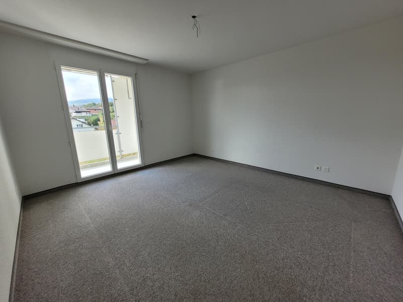 Empty room, white walls, carpeted floor, sliding glass door with balcony, electrical outlets