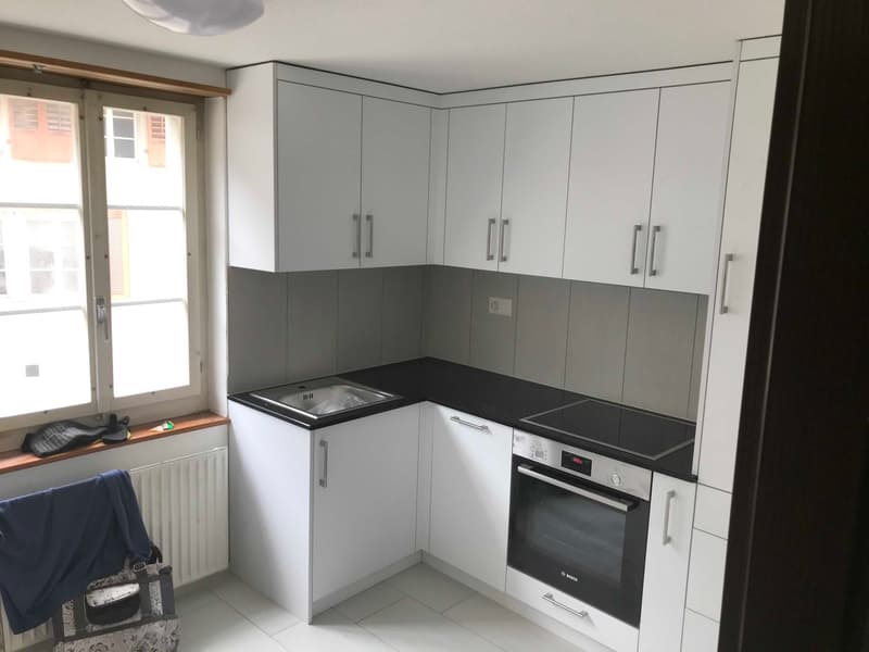 white cabinets, black countertop, integrated sink, oven and dishwasher, large window