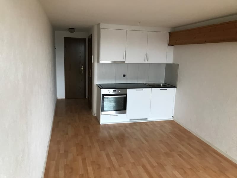 an empty kitchen with white cabinets, wooden floor, and appliances