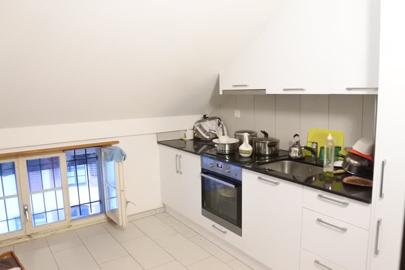 White cabinets, tiled floor, stainless steel appliances, black countertop, window with view outside