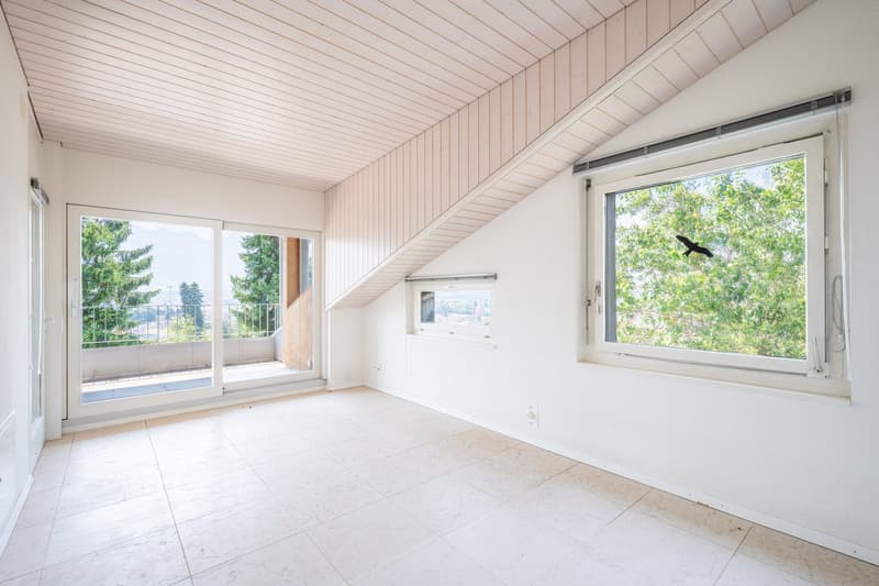 empty room, white walls, white tile floor, large windows, balcony with railings, view of trees and mountains