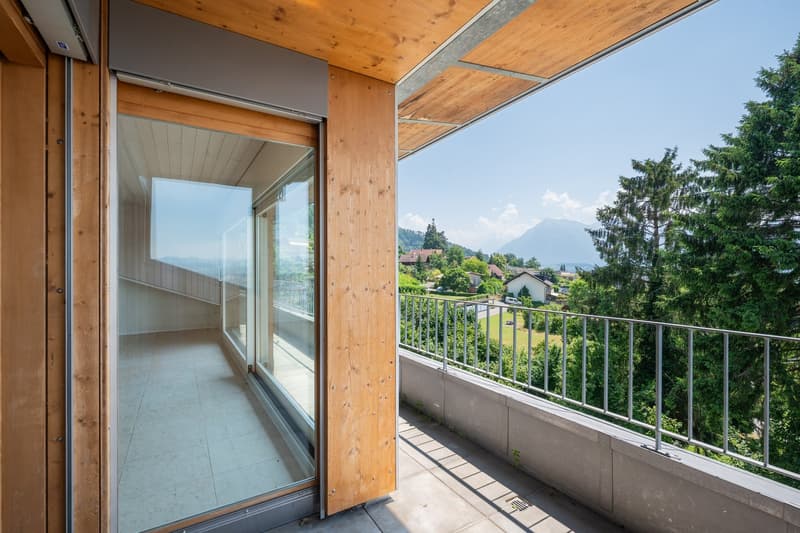 Balcony with glass door, wooden railing, tiled floor, view of mountains and trees