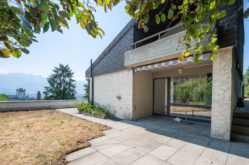modern house, concrete and brick walls, large windows, balcony, tiled entrance, small garden