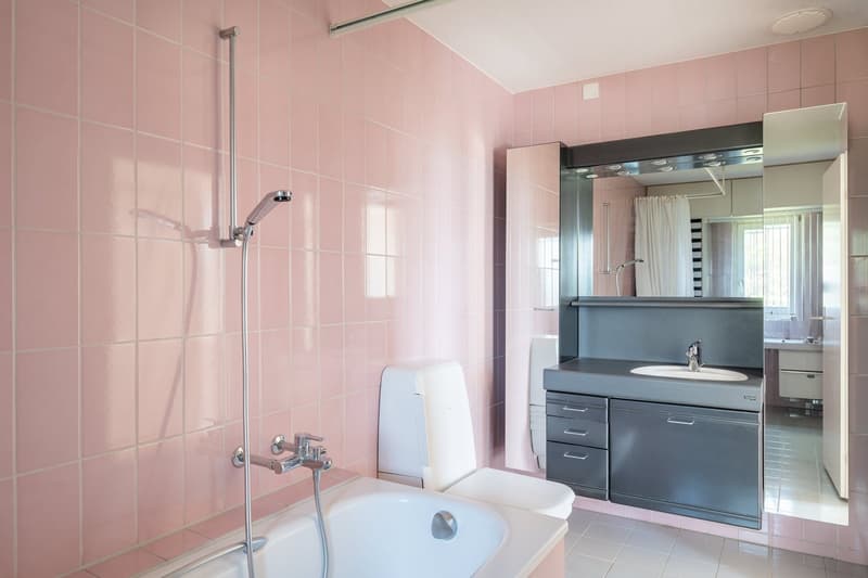 Bathroom with pink tiles, bathtub, shower, sink, mirror, and toilet