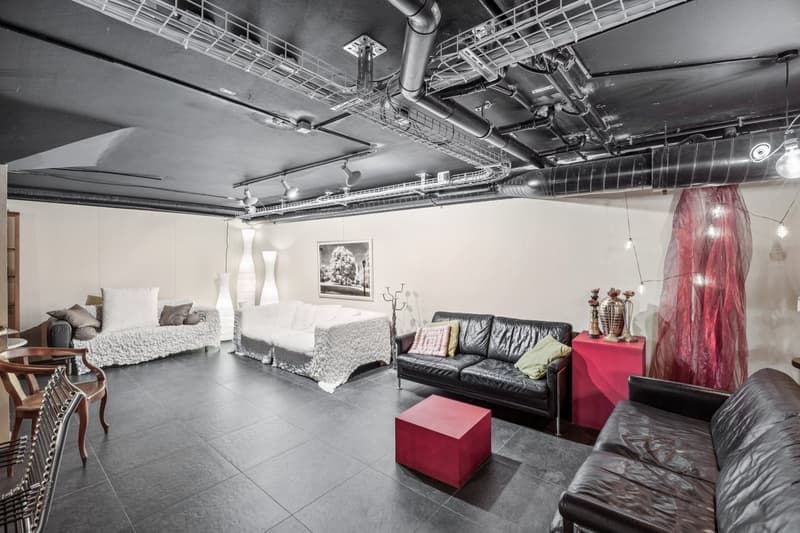 Large open room with multiple couches, a central coffee table, two small tables, a red shelf and several floor lamps