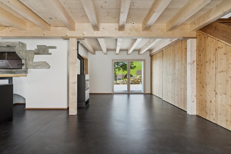 Fireplace, wooden beams, concrete floor, sliding glass doors to garden