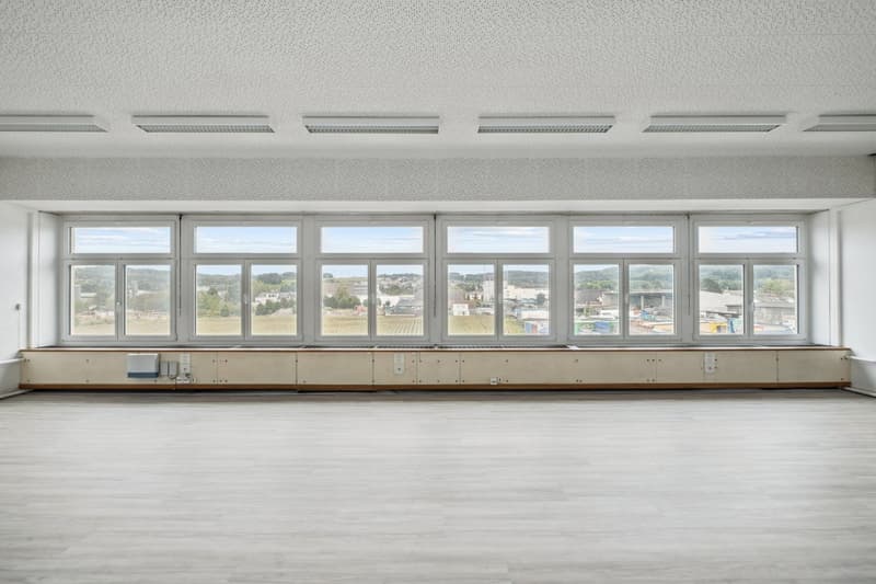 wide room, large windows, empty floor, white walls and ceiling