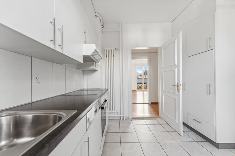 modern kitchen with white cabinets, black countertops, stainless steel sink, dishwasher, electrical outlet, and a window