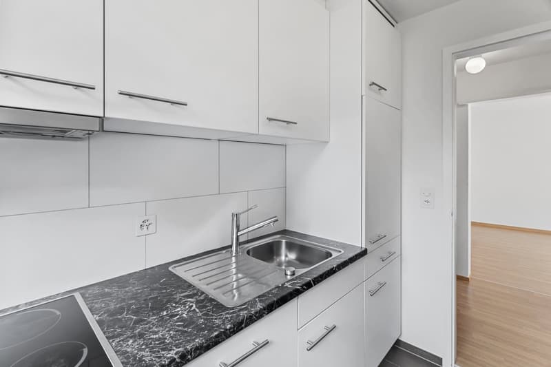 modern kitchen with white cabinets, marble countertop, stainless steel sink, faucet, electrical outlet, and power outlet