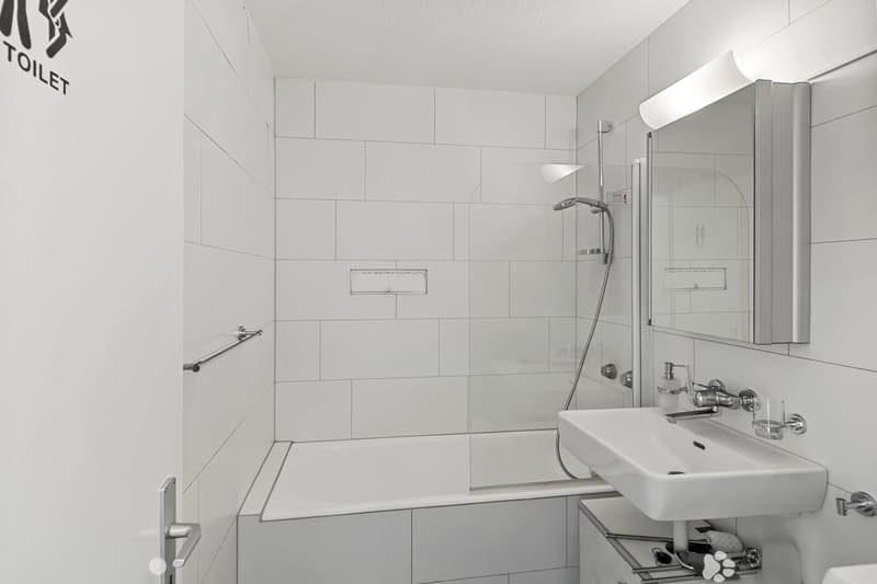 modern bathroom with white tiles, bathtub, shower, sink, mirror, and a glass door