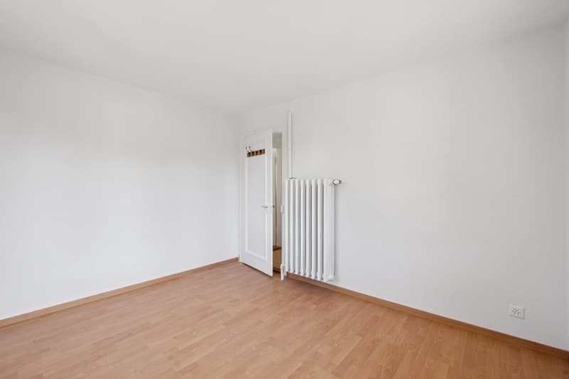 empty room, white walls, wooden floor, white radiator, open door