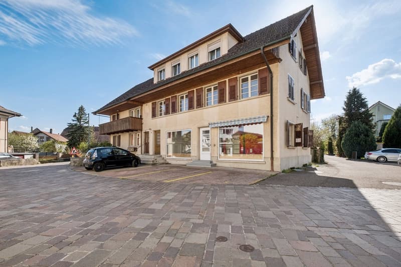 3 story house, beige exterior, brown roof, multiple windows, balcony, parking lot