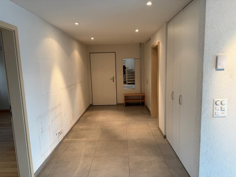 White walls, tiled floor, closed doors, power outlets, small shelf