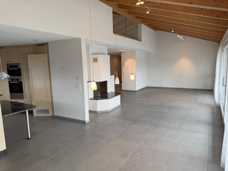 modern kitchen with wooden countertops, stainless steel oven, large empty room with white walls, grey tile flooring, wooden ceiling with lights