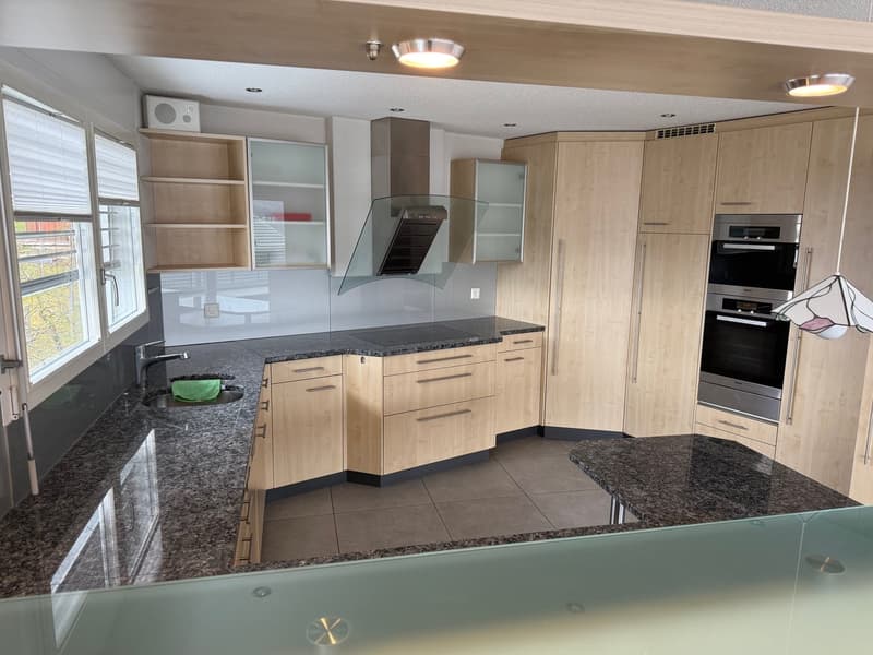 modern kitchen with granite countertops, wooden cabinets, integrated appliances, and a central island